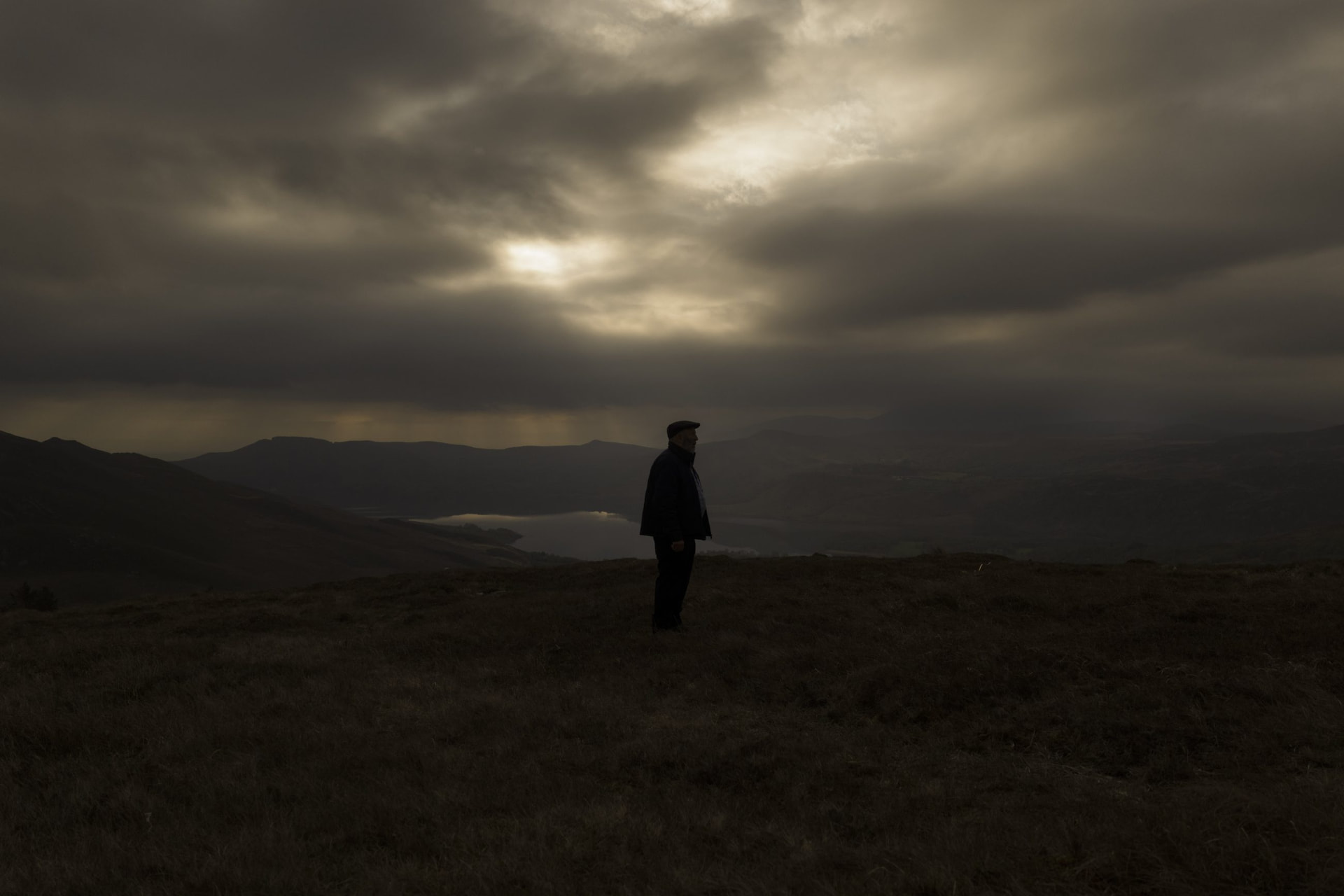A lone figure silhouetted on a Kerry mountainside at dusk under a dramatic sky